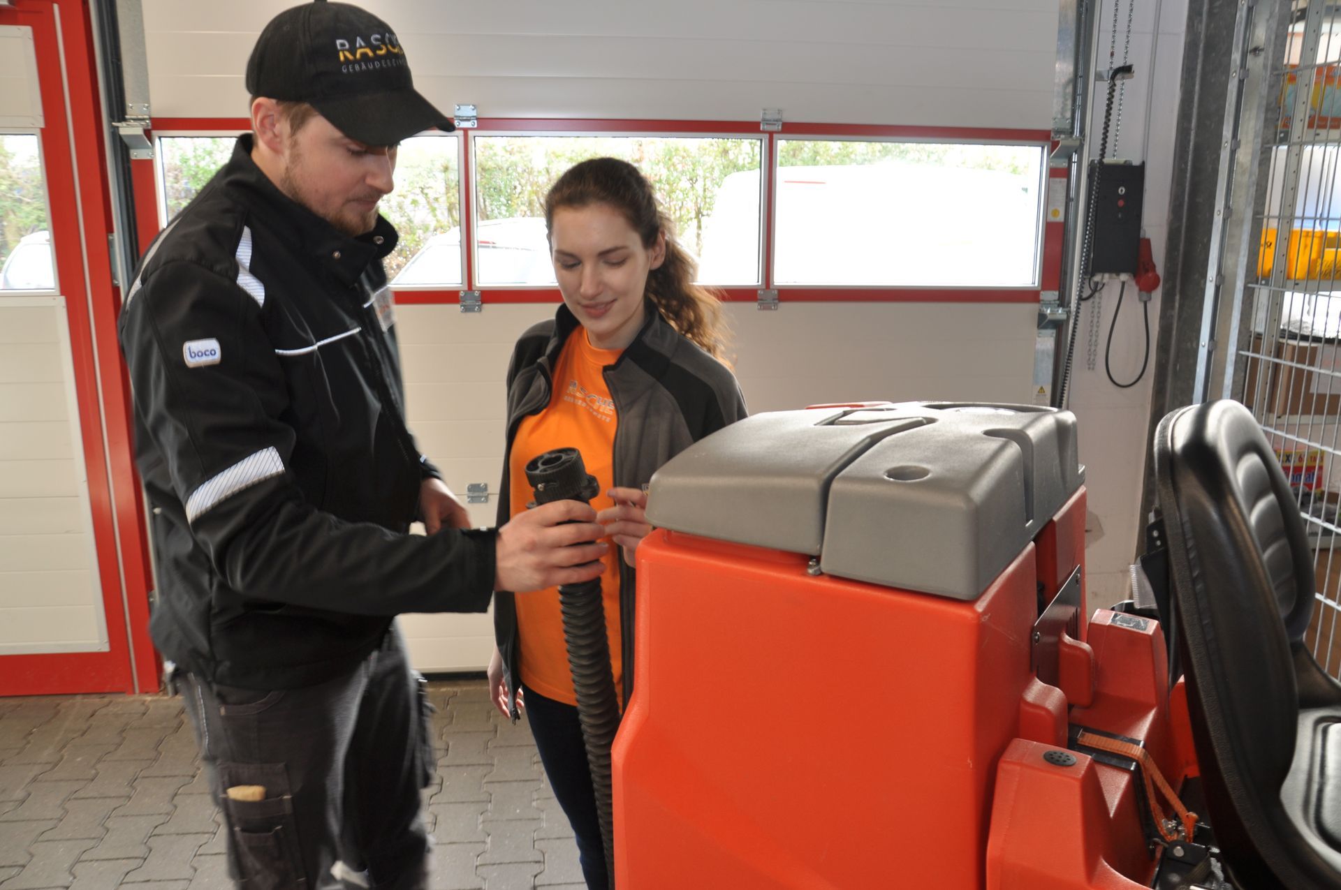 Ein Mann und eine Frau betrachten eine Maschine in einer Garage.