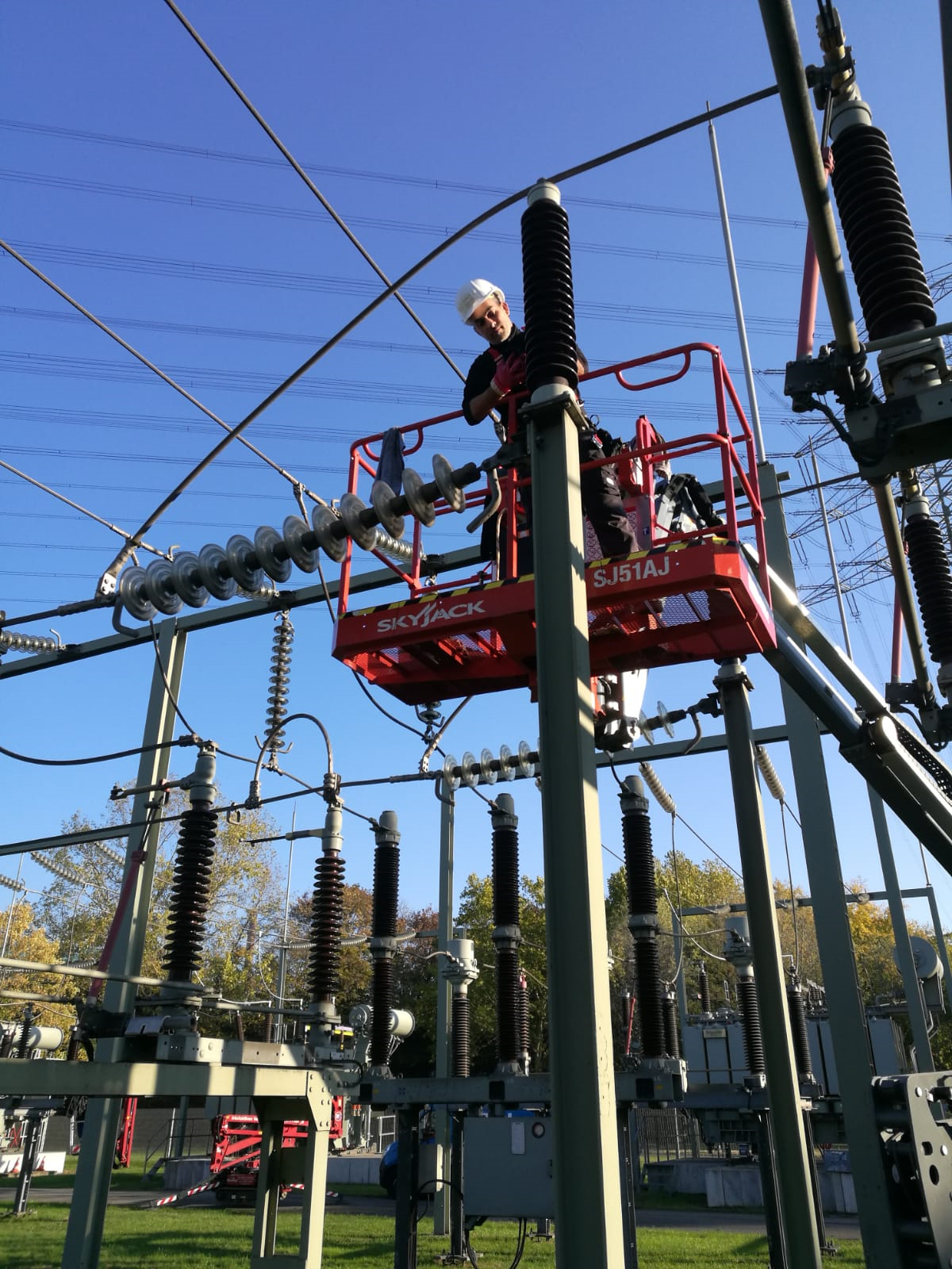 Ein Mann steht auf einer Hubarbeitsbühne und reinigt Isolatoren.