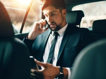 Homme en costume au téléphone en voiture