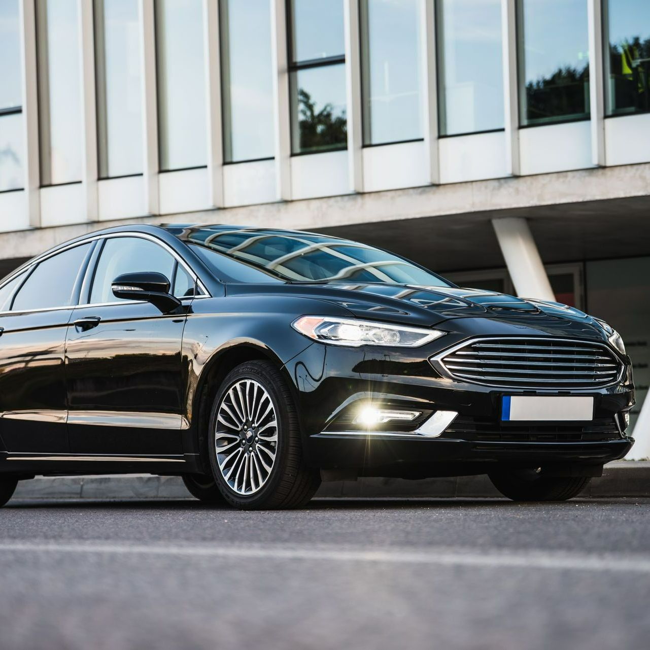 Voiture noire devant un bâtiment vitré