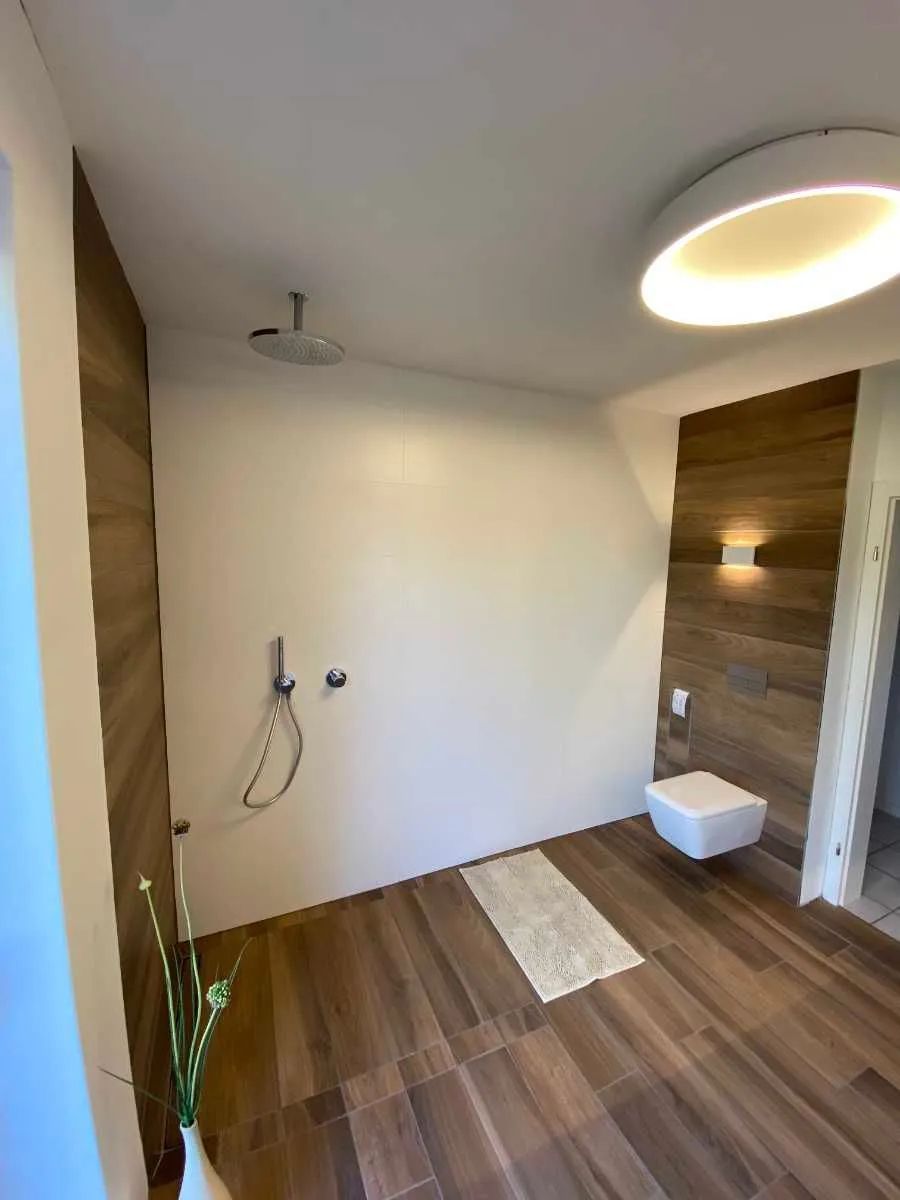 Saniertes Komplettbad mit ebenerdiger Dusche und Holzapplikationen