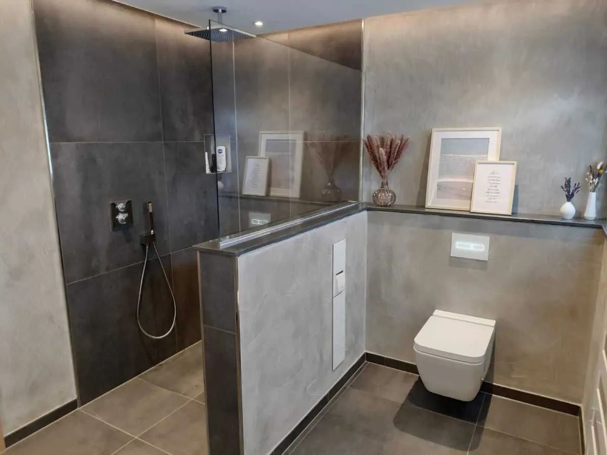 Komplettbad in Betonoptik mit ebenerdiger Duschkabine und Trennwand zur Toilette