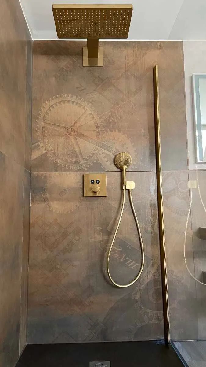 Komplettbad mit ebenerdiger Dusche, gold-brauner Einrichtung und Fliesen mit gedruckten Zahnrädern
