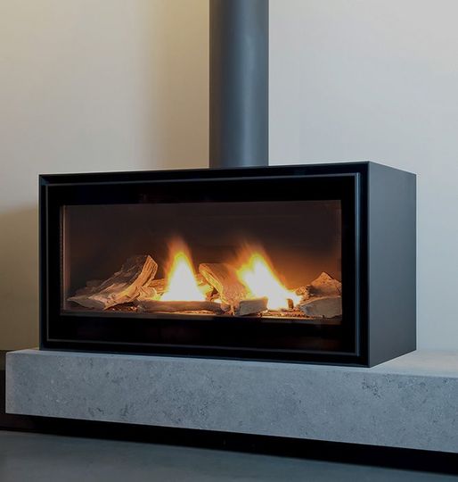 Poêle rectangulaire posé sur une plateforme aspect pierr avec une vitre frontale, des flammes visibles à l’intérieur et des bûches.