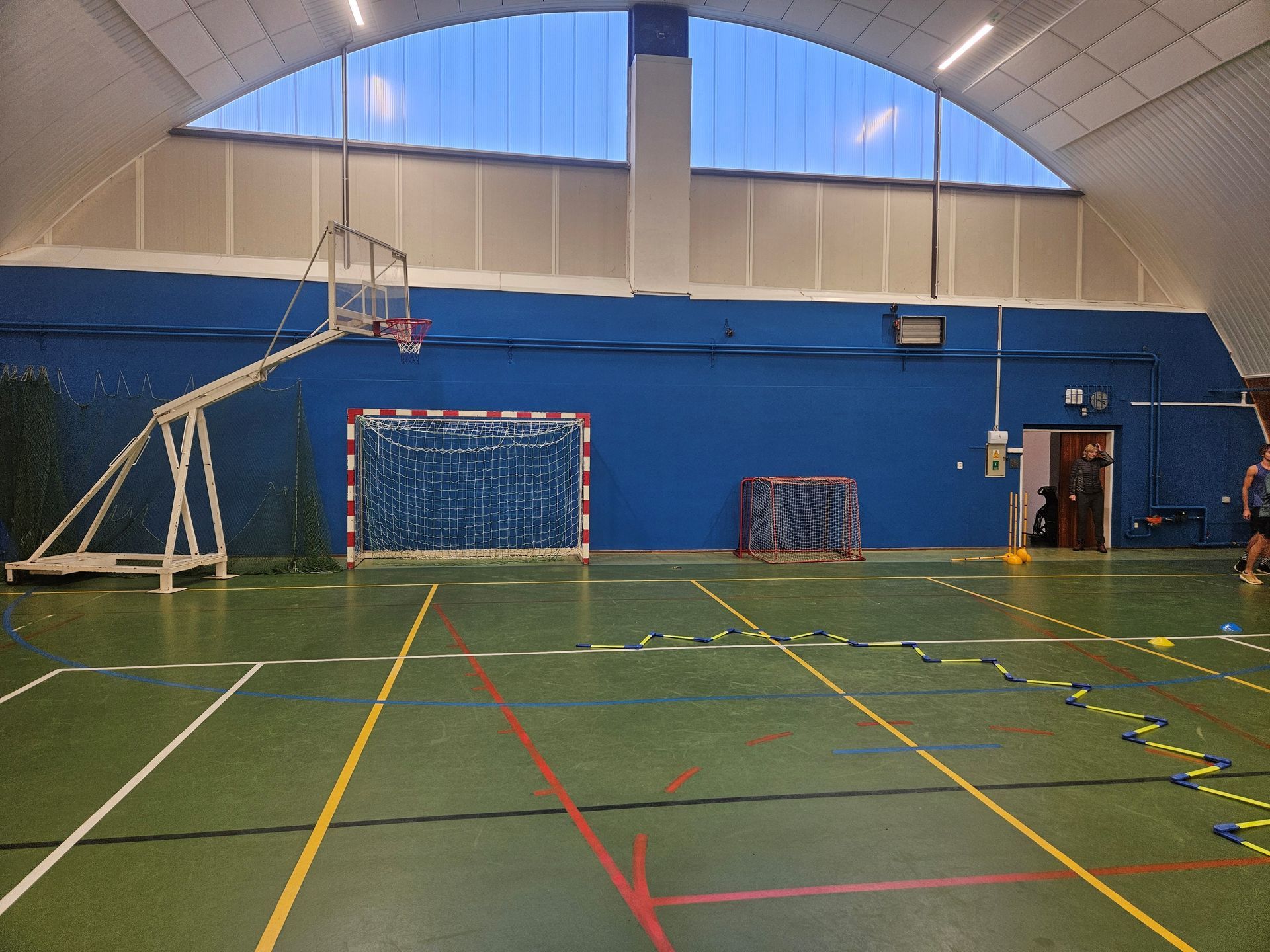 Volleyball in der Luft über dem Netz, die Hände zum Blocken nach oben ausgestreckt; Arena-Setting.