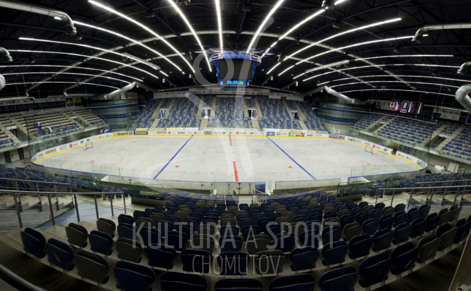Das Interieur einer Eishockeyarena mit blauen Sitzen, Eisfläche und Deckenbeleuchtung.