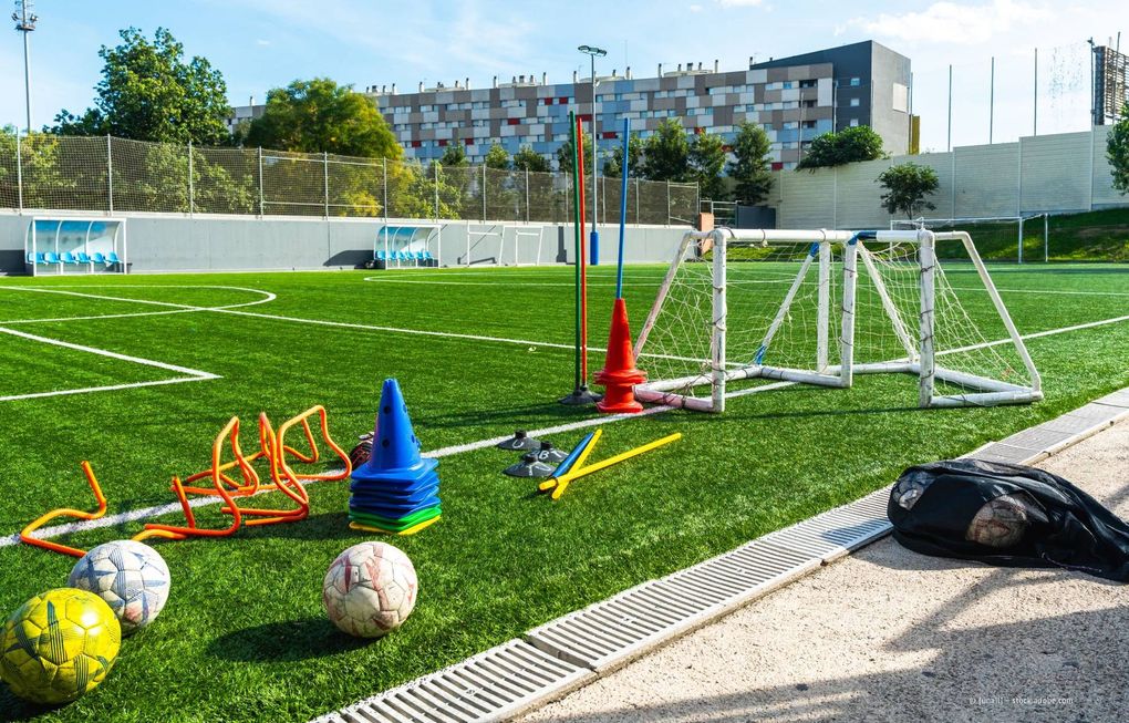 Fußballfeld mit Trainingsgeräten: Hütchen, Minitore, Hürden, Bälle.