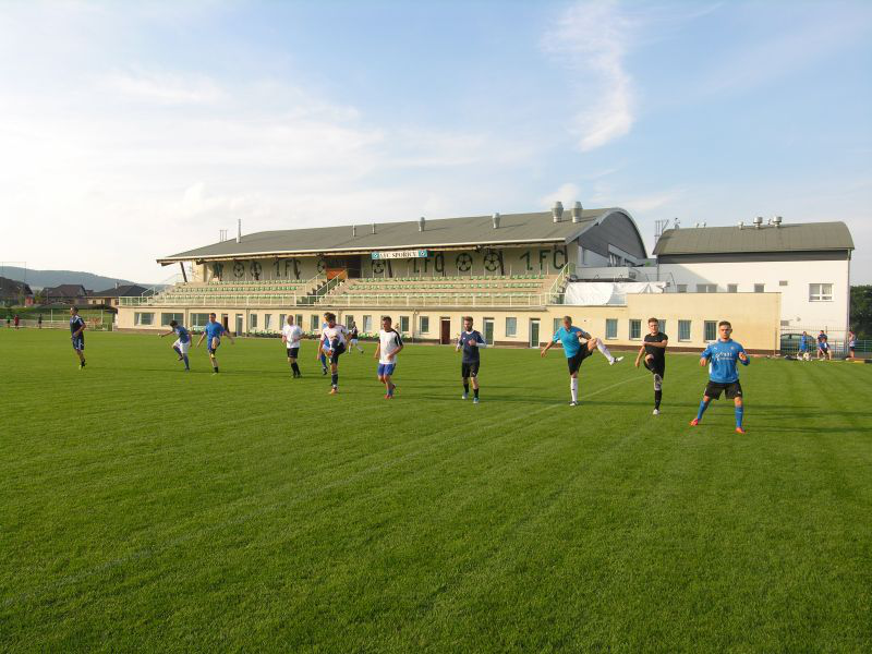 Fußballspieler dehnen sich an einem sonnigen Tag auf einem grünen Rasen vor dem Stadion.
