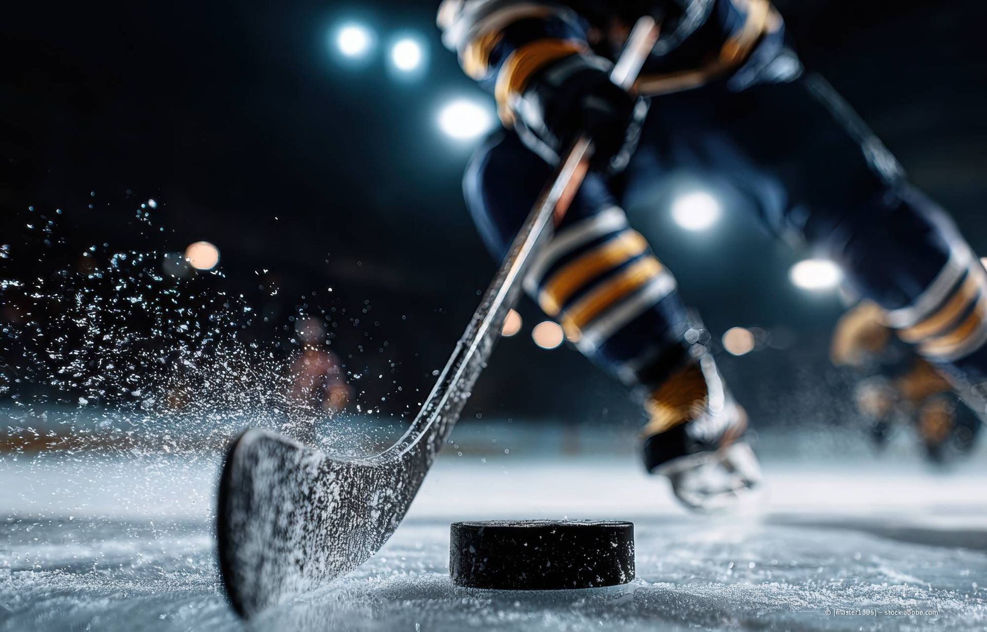 Eishockeyspieler im Begriff, den Puck zu schießen, Eisbahn, Fokus auf Puck und Schläger.
