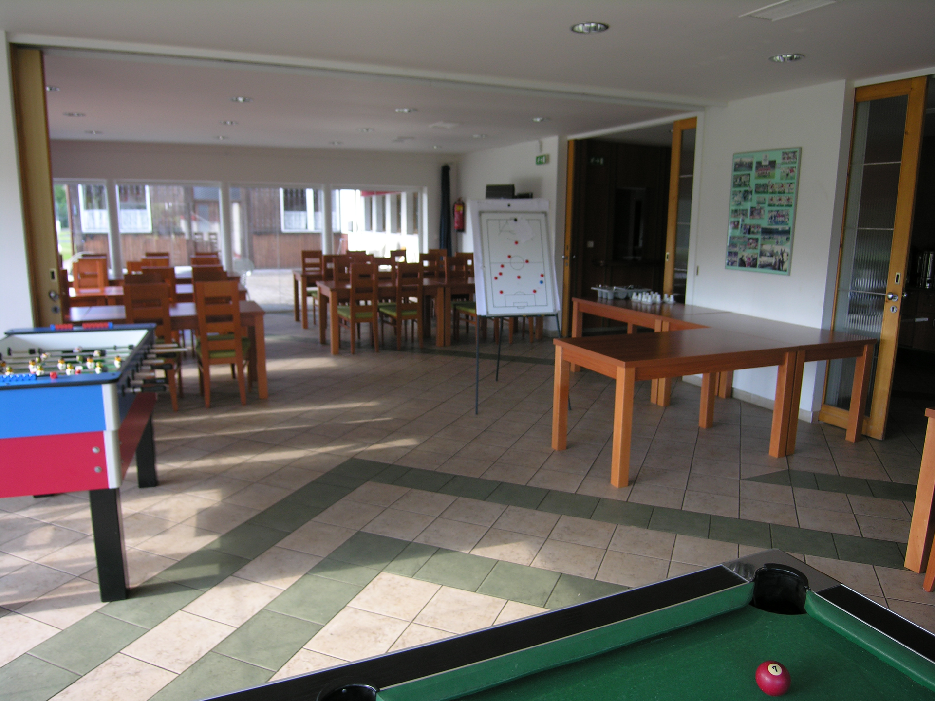 Spielzimmer mit Tischfußball, Billardtisch, Tischen, Stühlen und Whiteboard.