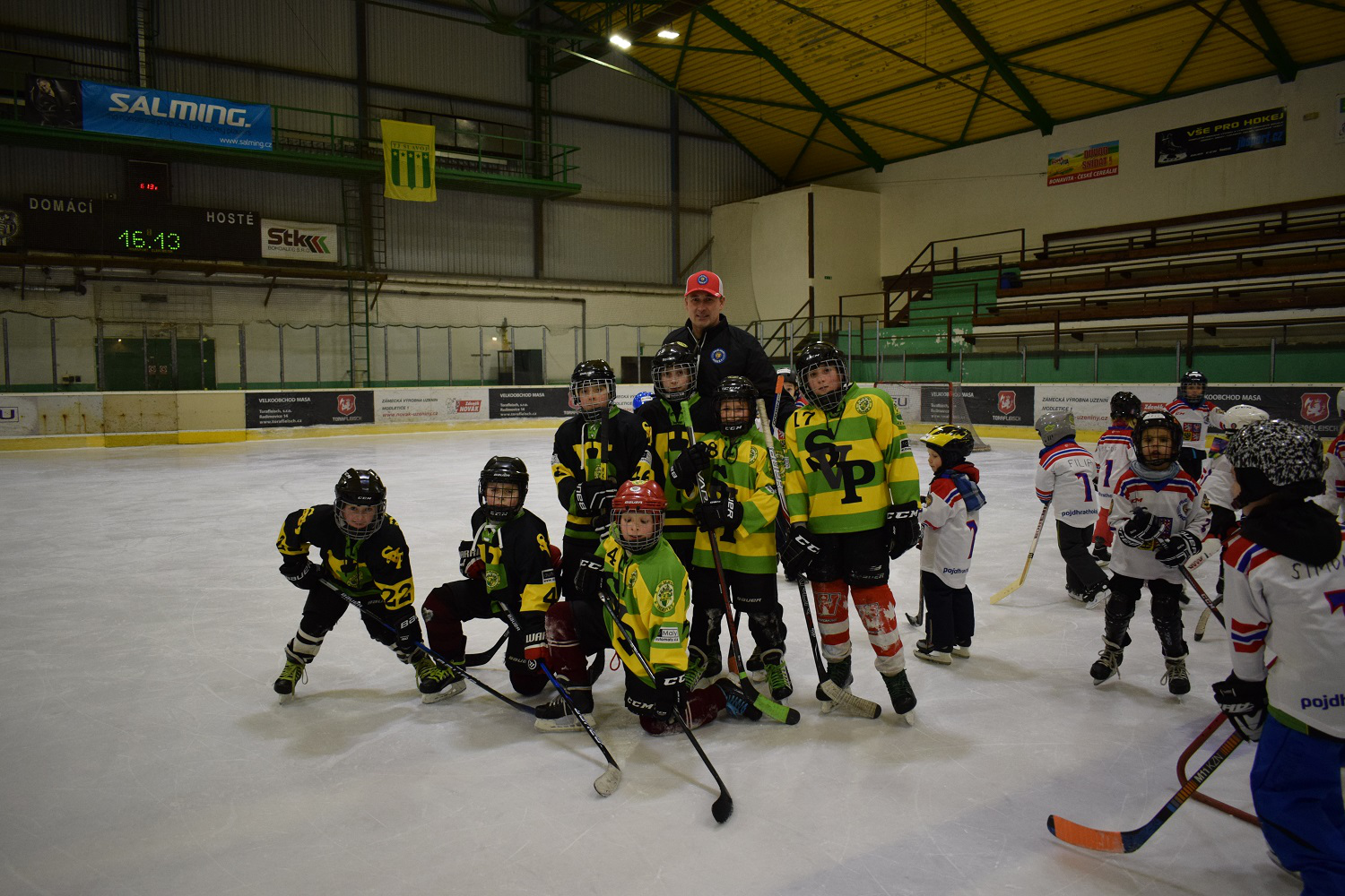 Eine Jugend-Eishockeymannschaft posiert mit ihrem Trainer auf dem Eis im Stadion.