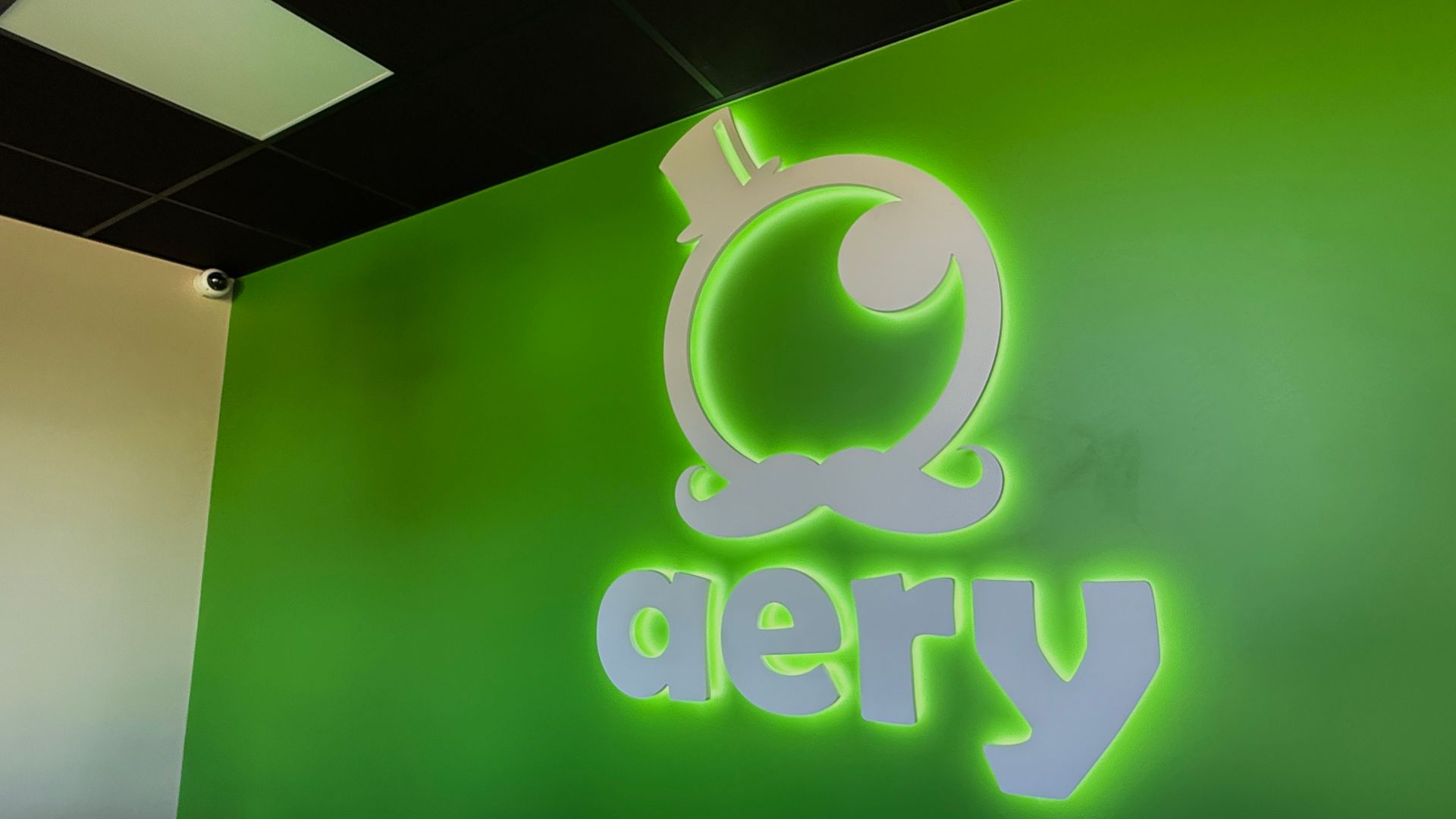 Mur vert avec logo « aery » blanc illuminé dans un environnement de bureau intérieur
