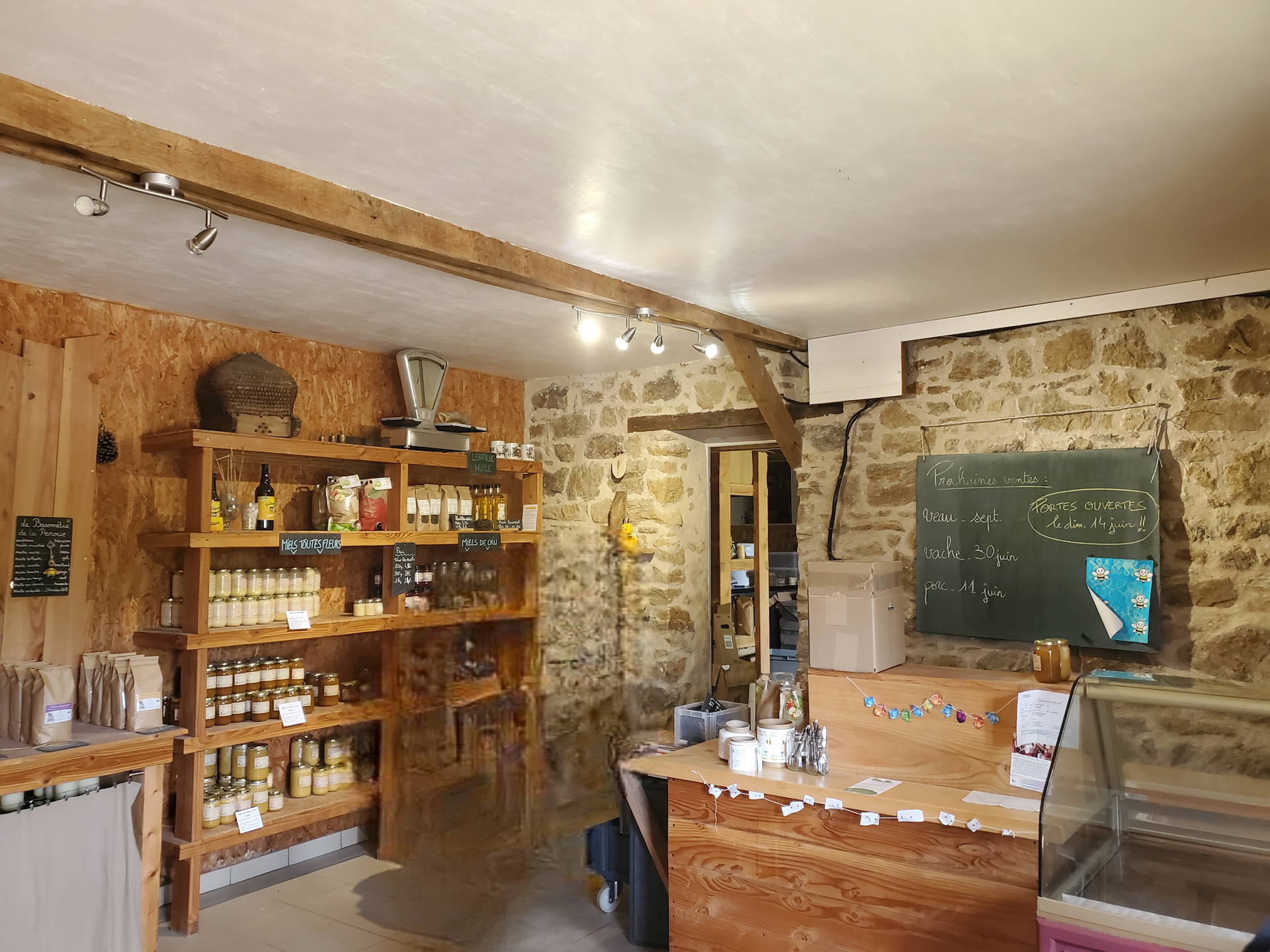 Intérieur rustique d'un café aux murs de pierre, avec étagères en bois, menu à la craie et comptoir sous un éclairage chaleureux.