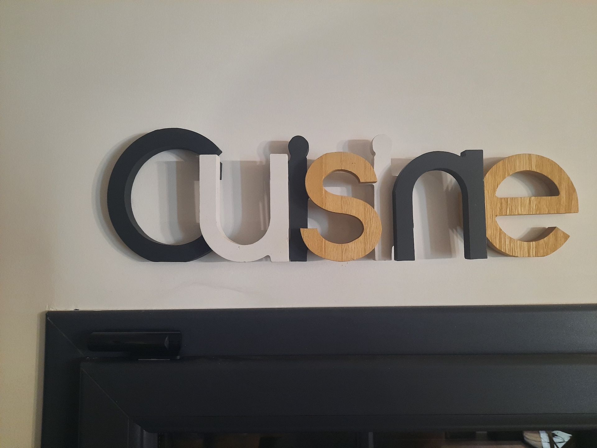 Panneau mural « Cuisine » noir, blanc et or au-dessus d'une télévision