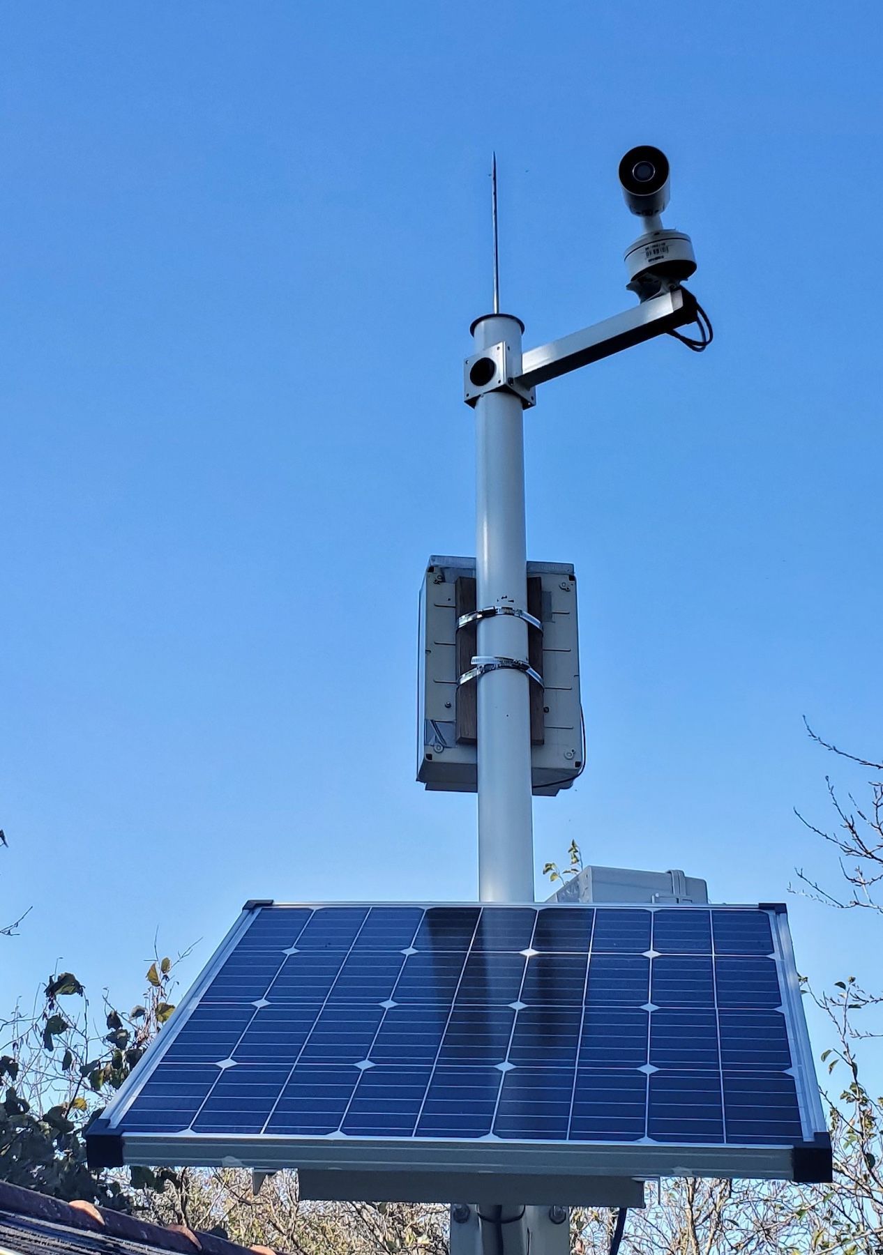 Panneau solaire monté sur un mât avec antennes et capteurs sur fond de ciel bleu