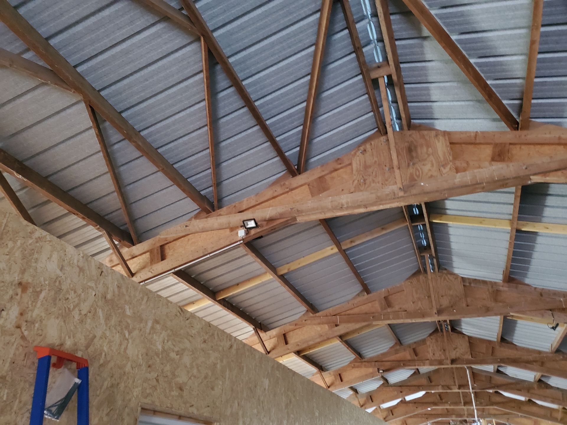 Intérieur d'un bâtiment à toiture métallique avec charpente apparente en bois et murs en pierre