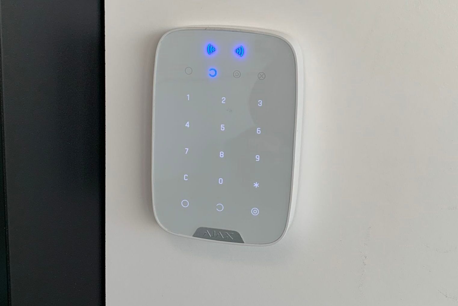 Clavier lumineux mural fixé sur un mur blanc près d'une porte.