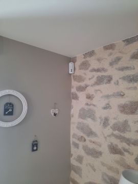 Coin d'une pièce aux murs gris à motifs de pierre, un miroir rond et un petit objet de décoration murale.