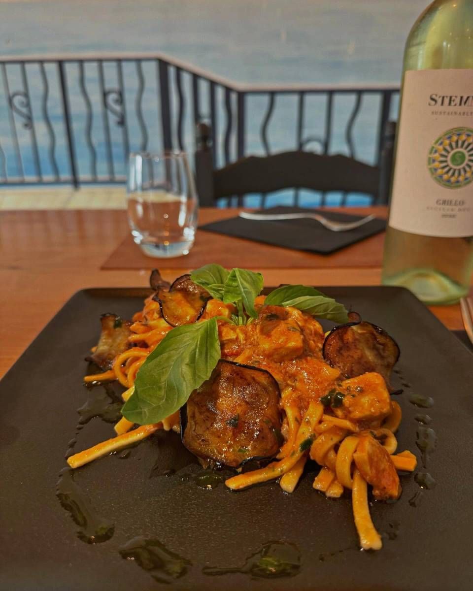 Une assiette de nourriture est posée sur une table à côté d'une bouteille de vin.