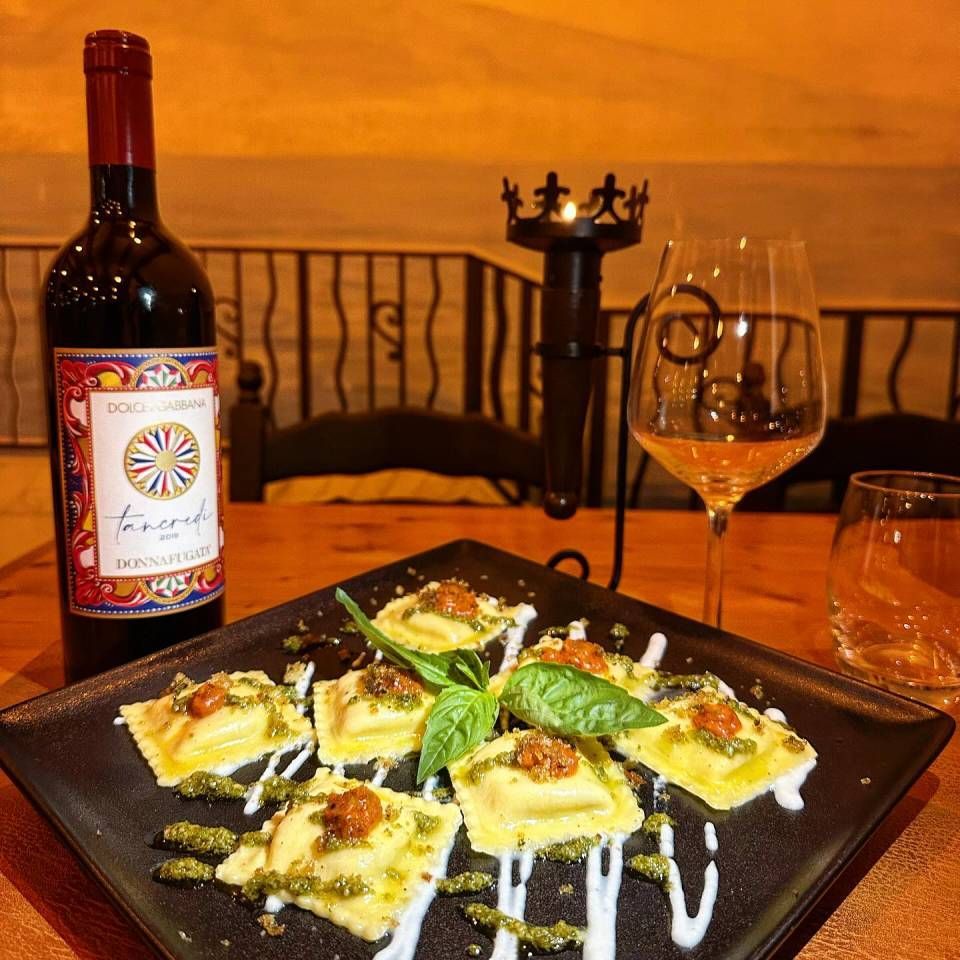 Une bouteille de vin est posée à côté d'une assiette de raviolis