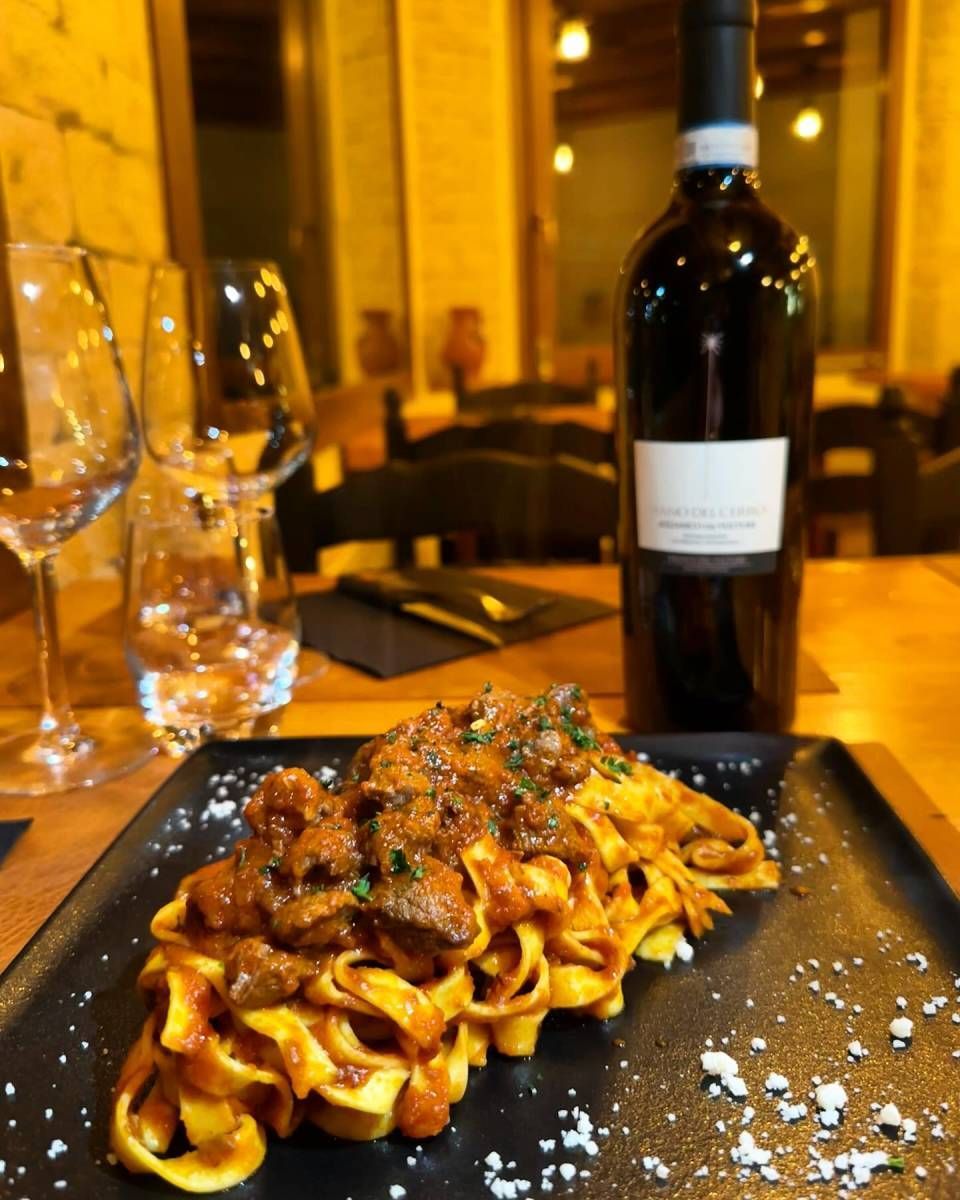 Une bouteille de vin est posée à côté d'une assiette de pâtes