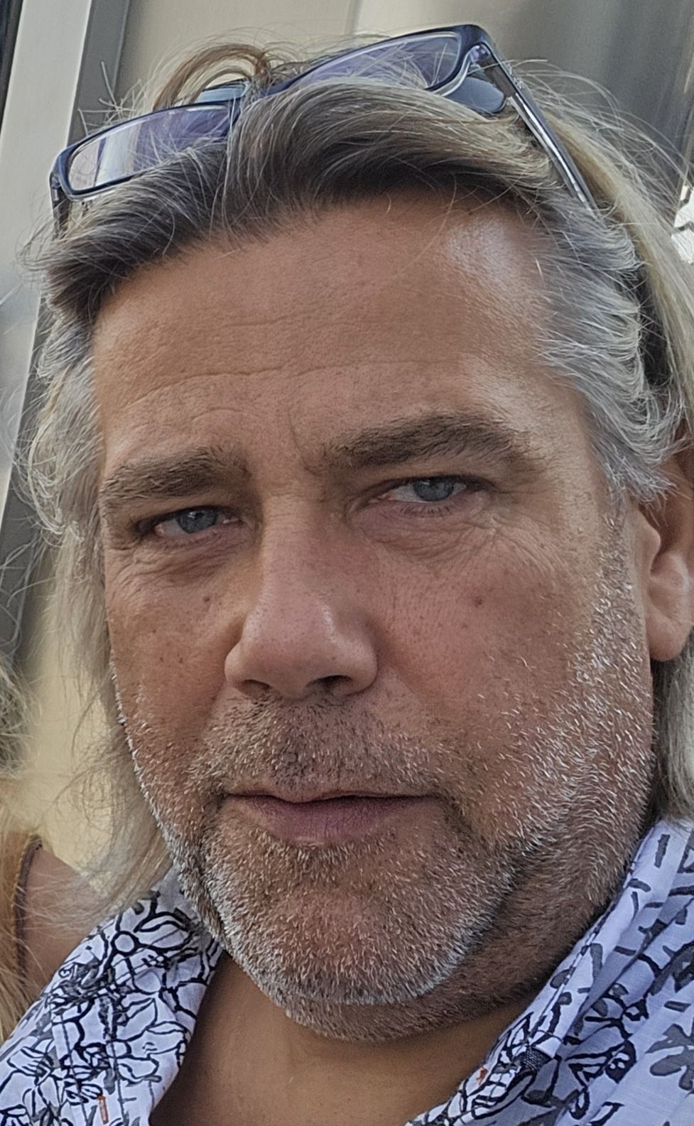 Ein Mann mit langen Haaren und Ohrringen lächelt in die Kamera.