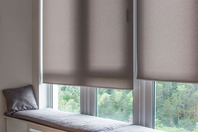 Ein Fenstersitz mit Kissen und Jalousien darauf