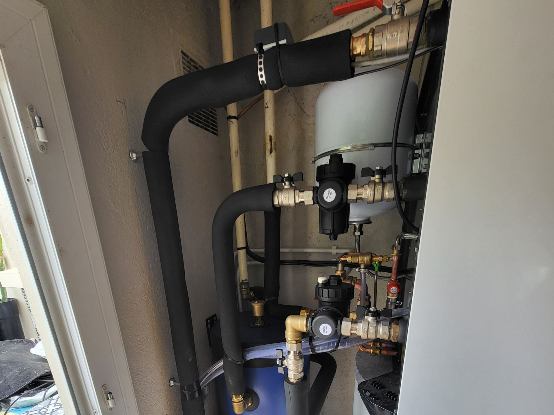 Tuyaux et vannes d'un système de chauffage, tuyaux isolés noirs, raccords en laiton, dans une niche.