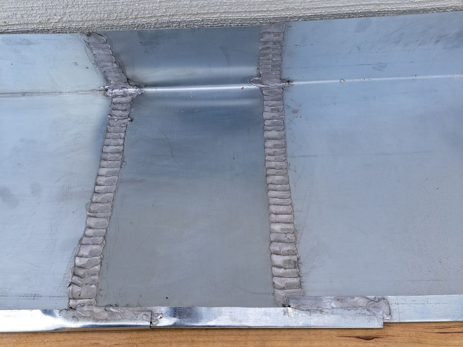 Gros plan sur des panneaux en zinc soudés, montrant les lignes de soudure et les joints métalliques visibles.
