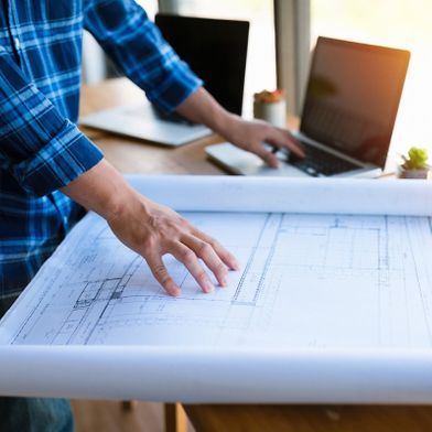 Zwei Hände mit Kugelschreiber über Bauplan