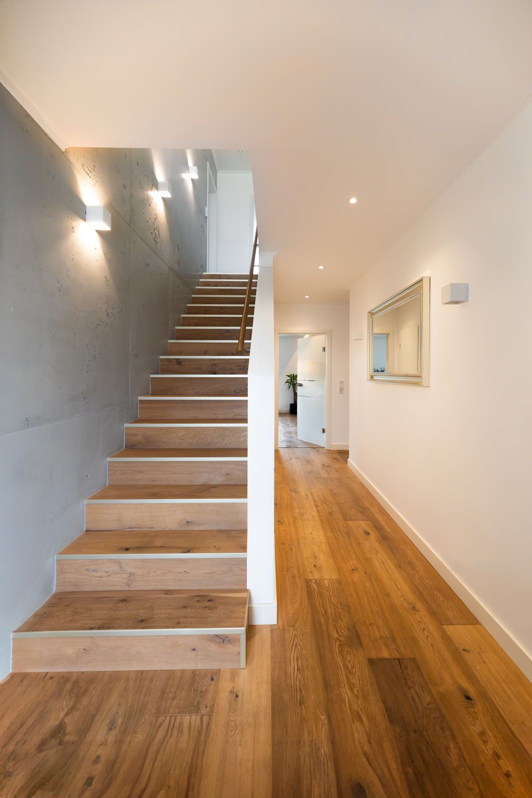 Ein Flur mit Holzboden und Treppe, die in den zweiten Stock führt.