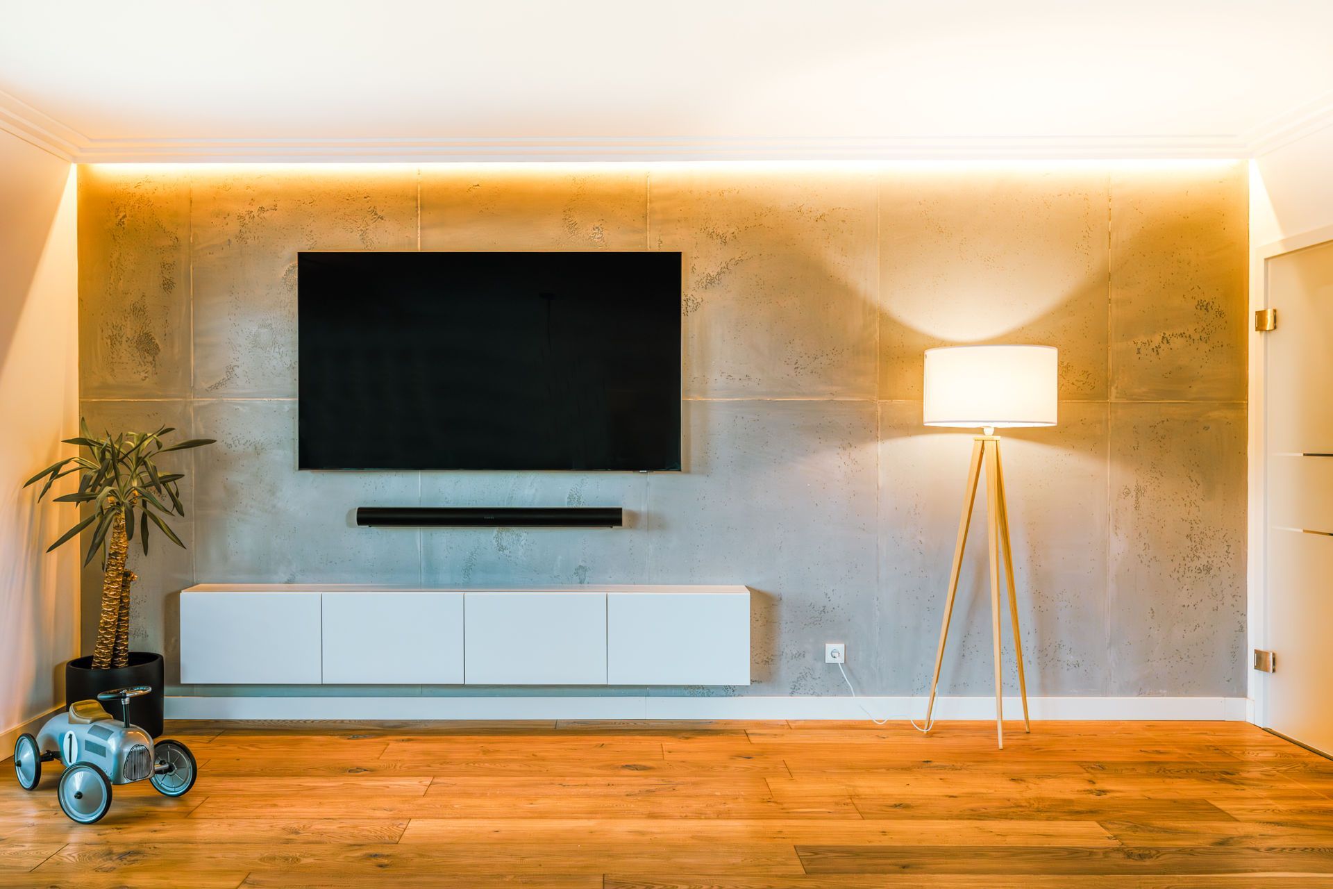 Ein Wohnzimmer mit einem Flachbildfernseher an der Wand und einer Lampe.