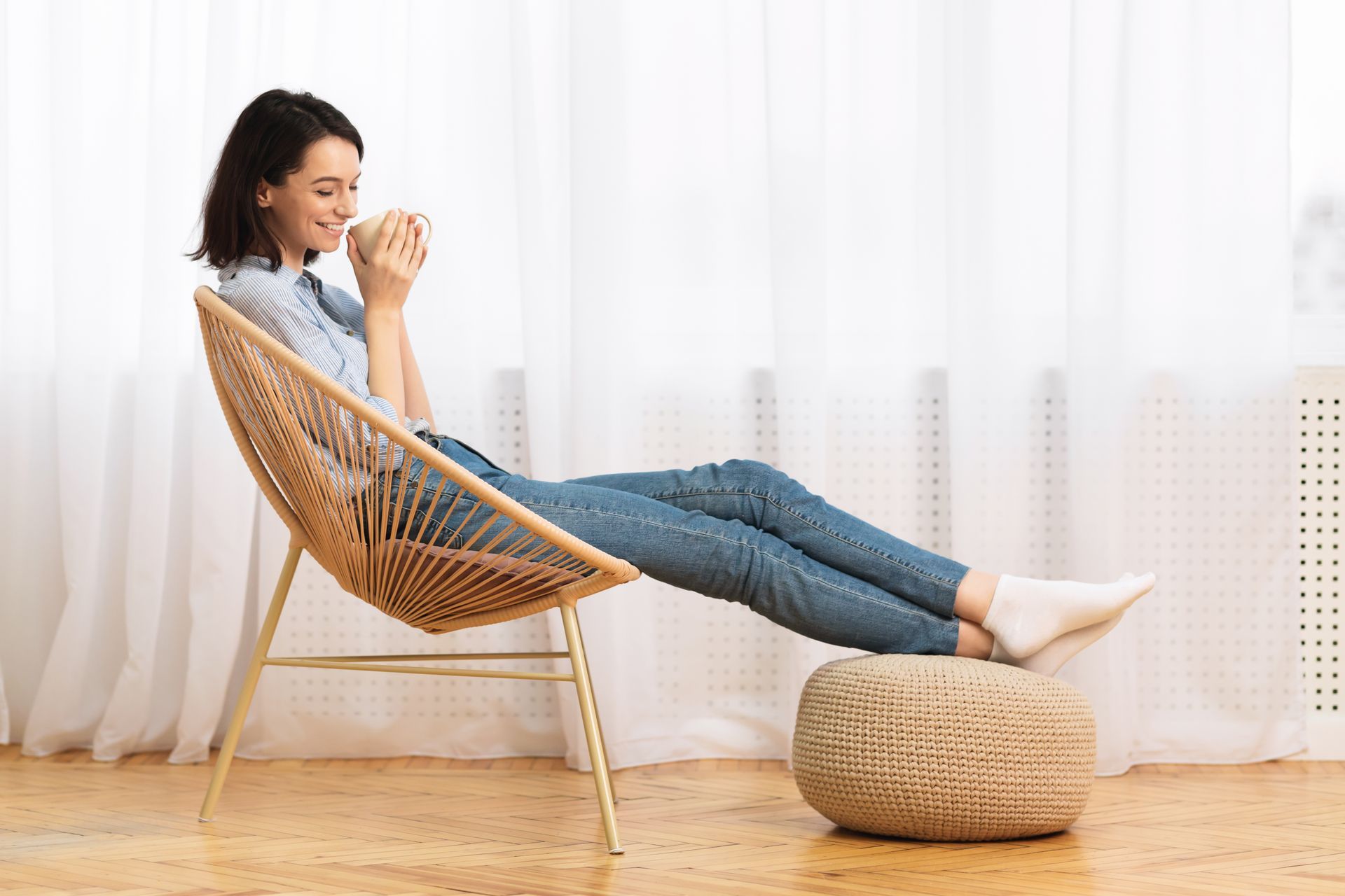 Eine Frau sitzt auf einem Stuhl und trinkt eine Tasse Kaffee.