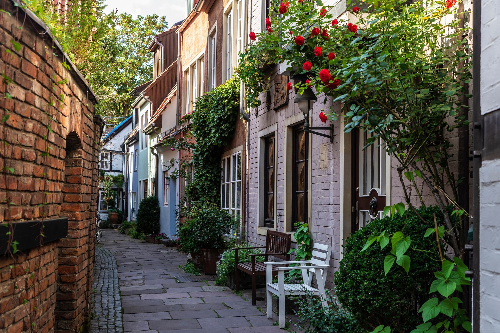 Eine schmale Gasse, gesäumt von Backsteingebäuden und Blumen.