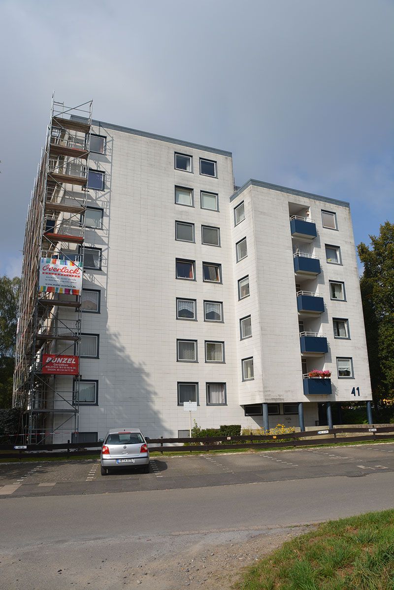 Ein weißes Gebäude mit einem davor geparkten Auto.