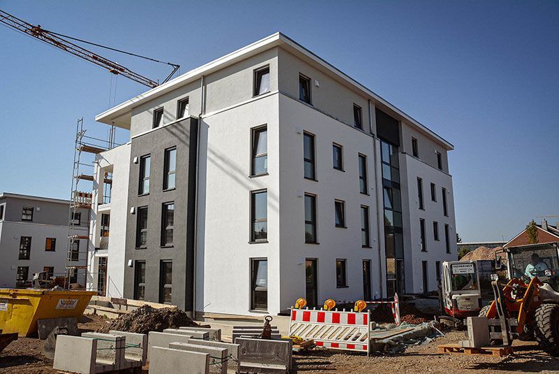 Ein großes weißes Gebäude wird gerade gebaut . Im Hintergrund ist ein Kran zu sehen.