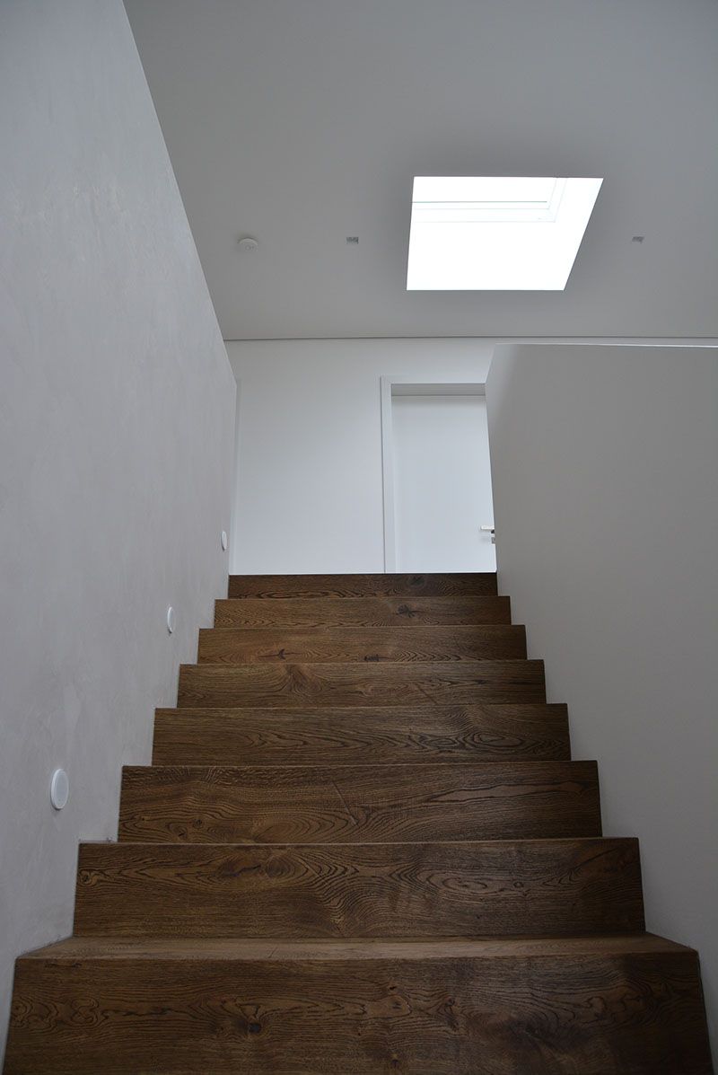 Eine Holztreppe führt zu einer weißen Wand hinauf.