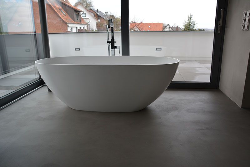 In einem Badezimmer steht eine Badewanne neben einem Fenster.