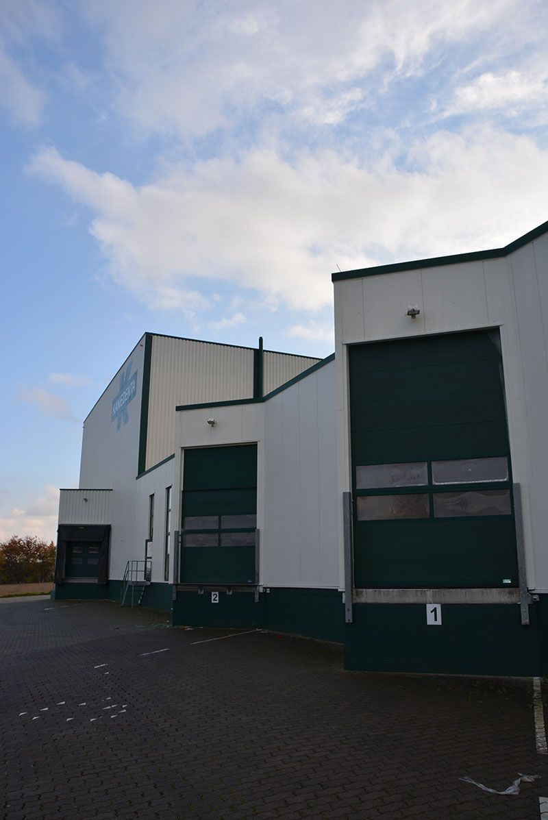 Ein weißes Gebäude mit grünen Türen und einem blauen Himmel im Hintergrund