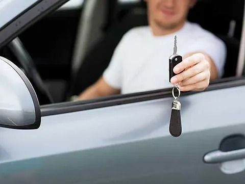 Un hombre está sentado en un coche sosteniendo una llave del coche.