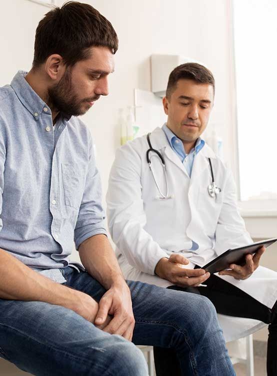 Un hombre está sentado en una sala de espera con un médico.