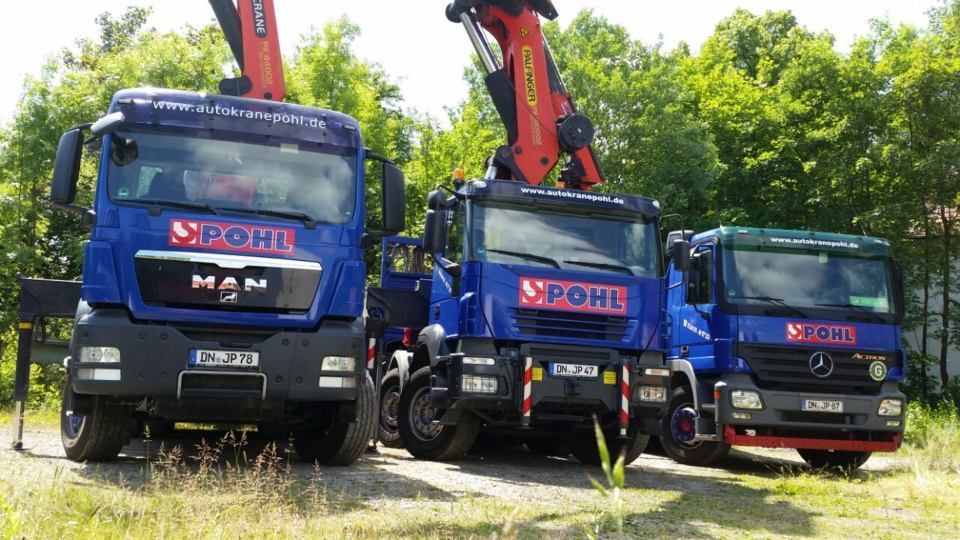 Auf einem Feld parken drei Lastwagen nebeneinander.