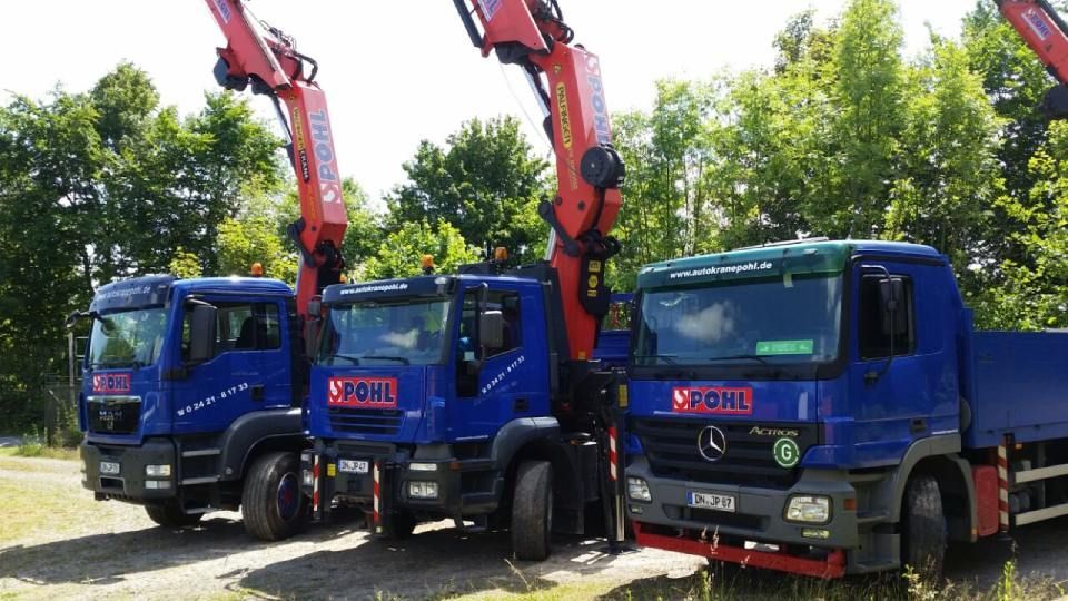 Drei Lastwagen parken nebeneinander auf einem Feldweg.