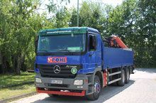 Ein blauer Lastwagen mit einem roten Kran steht am Straßenrand.