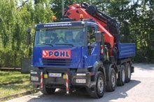 Ein blauer Lastwagen mit einem roten Kran auf der Ladefläche steht am Straßenrand.