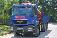 Ein blauer Lastwagen mit einem roten Kran steht am Straßenrand.