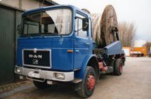 Ein blauer Lastwagen transportiert eine große Spule aus Holz.