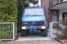 Ein blauer Lastwagen steht vor einem Haus.