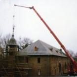 Mit einem großen Kran wird das Dach eines Gebäudes entfernt.