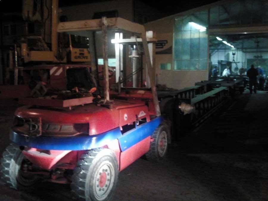 Ein rot-blauer Gabelstapler steht in einer dunklen Halle